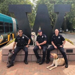 Officers in the K9 unit pose for a picture by the block W statue on 45th street.