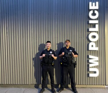 Two officers stand by UW Police sign