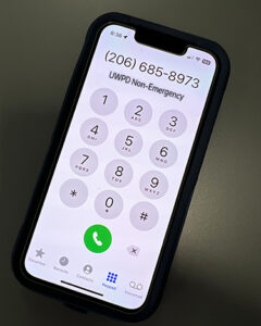 Black iPhone phone showing UWPD's non-emergency number on the screen, 206-685-8973.